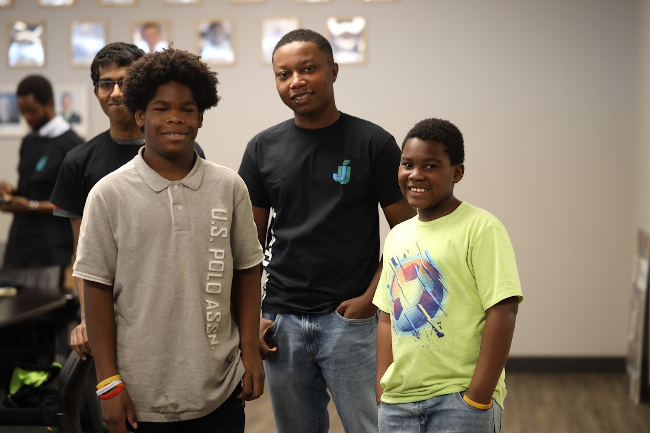 Four people standing together indoors, two of them in JustUsedTech shirts.