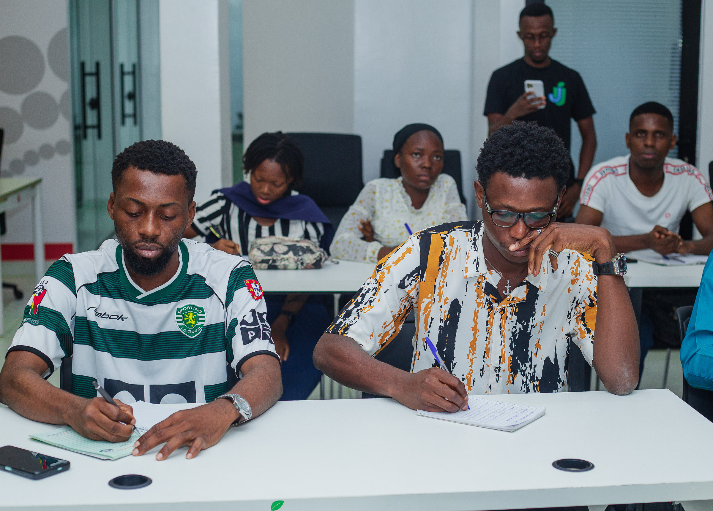 Participants seated at a long desk taking notes during a session.