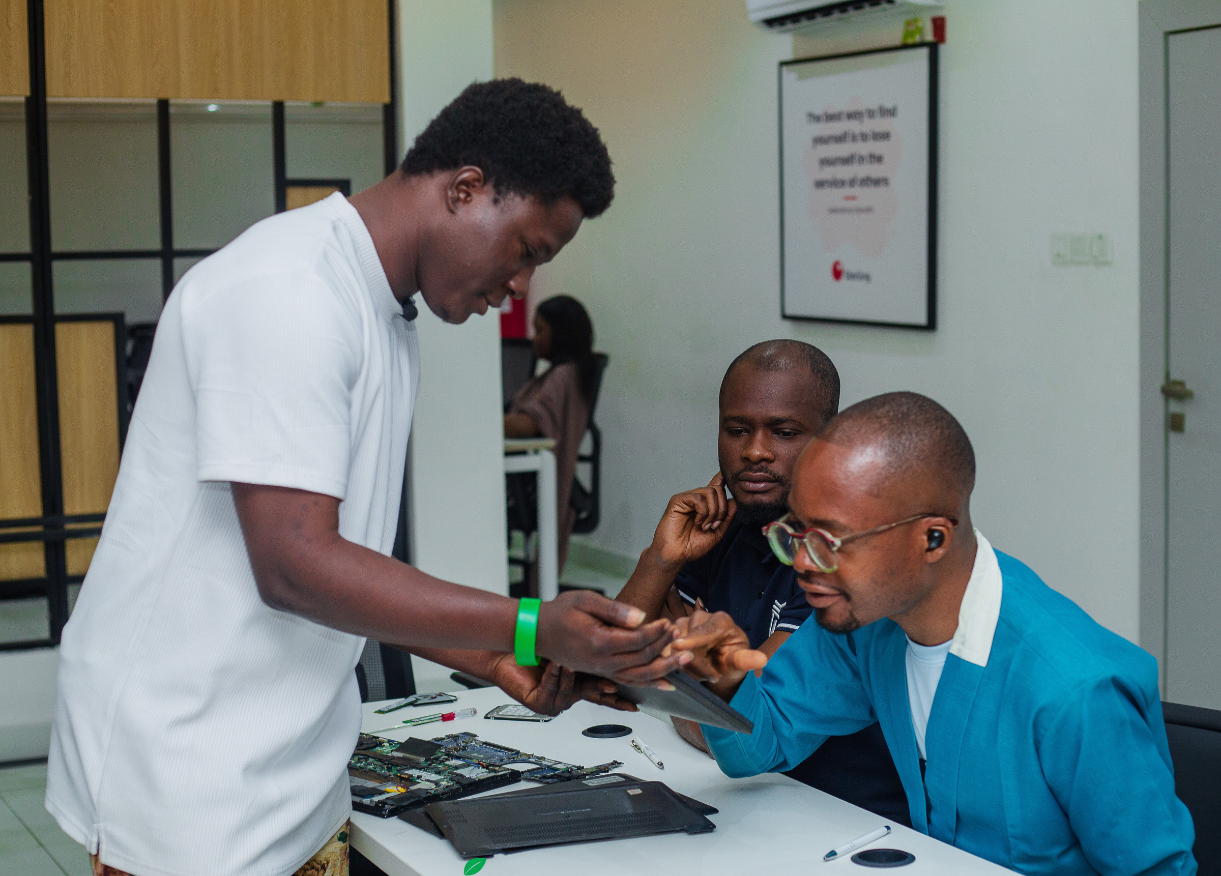 Two participants leaning over an opened laptop on a desk while a third looks on.
