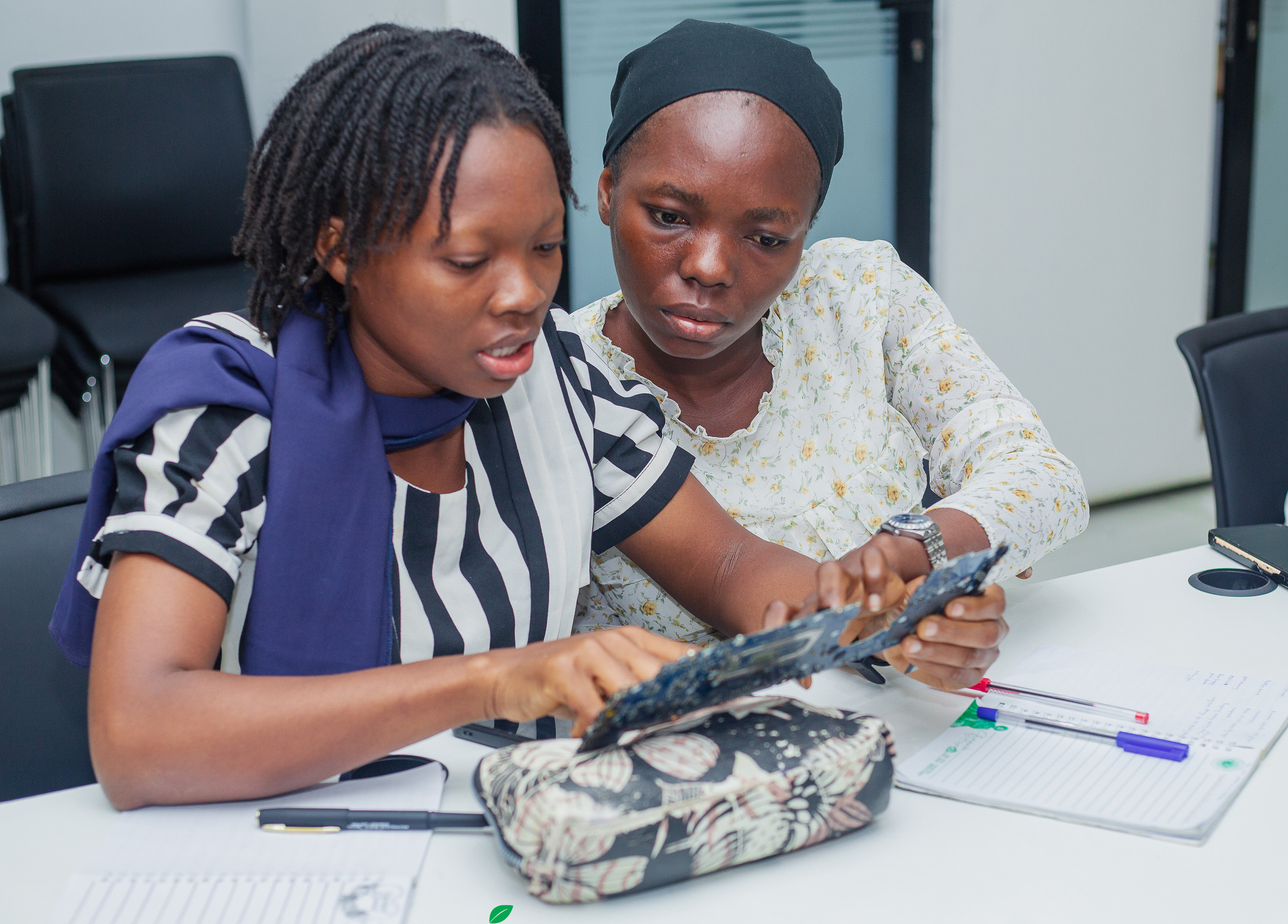 Two participants working together over a tablet at a desk.