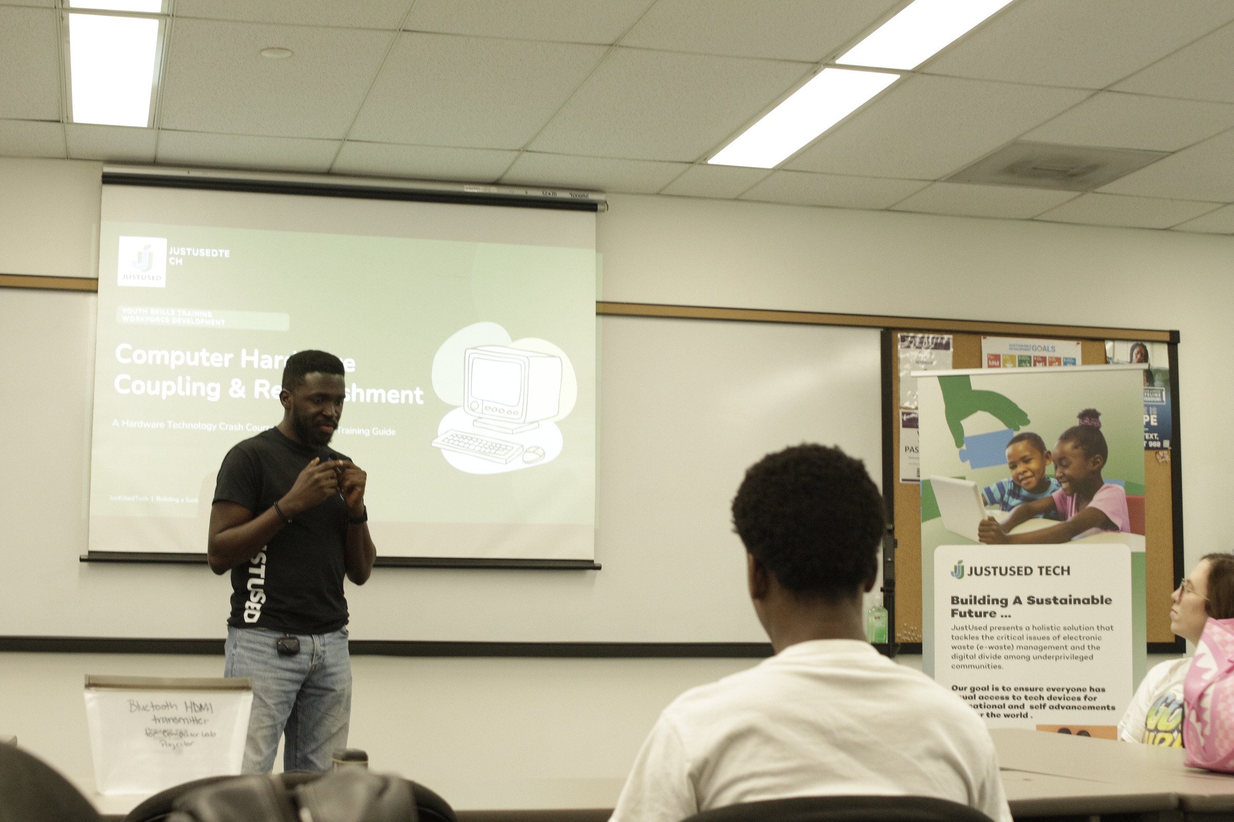 A facilitator presenting a slide headed Computer Hardware Coupling and Refurbishment to a seated audience.