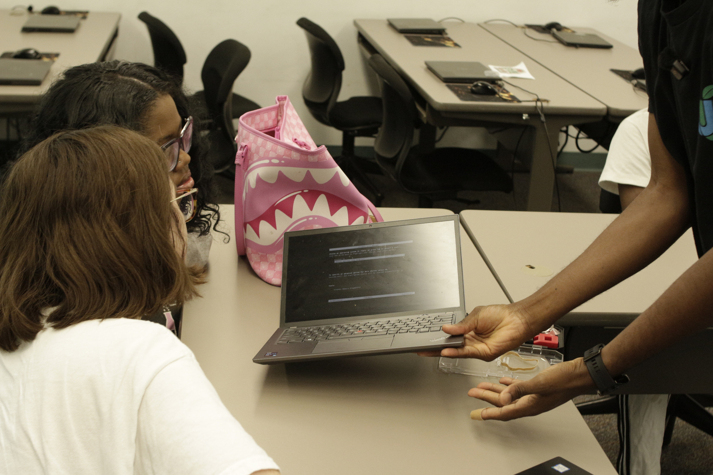 Participants at a table examining an open laptop together.