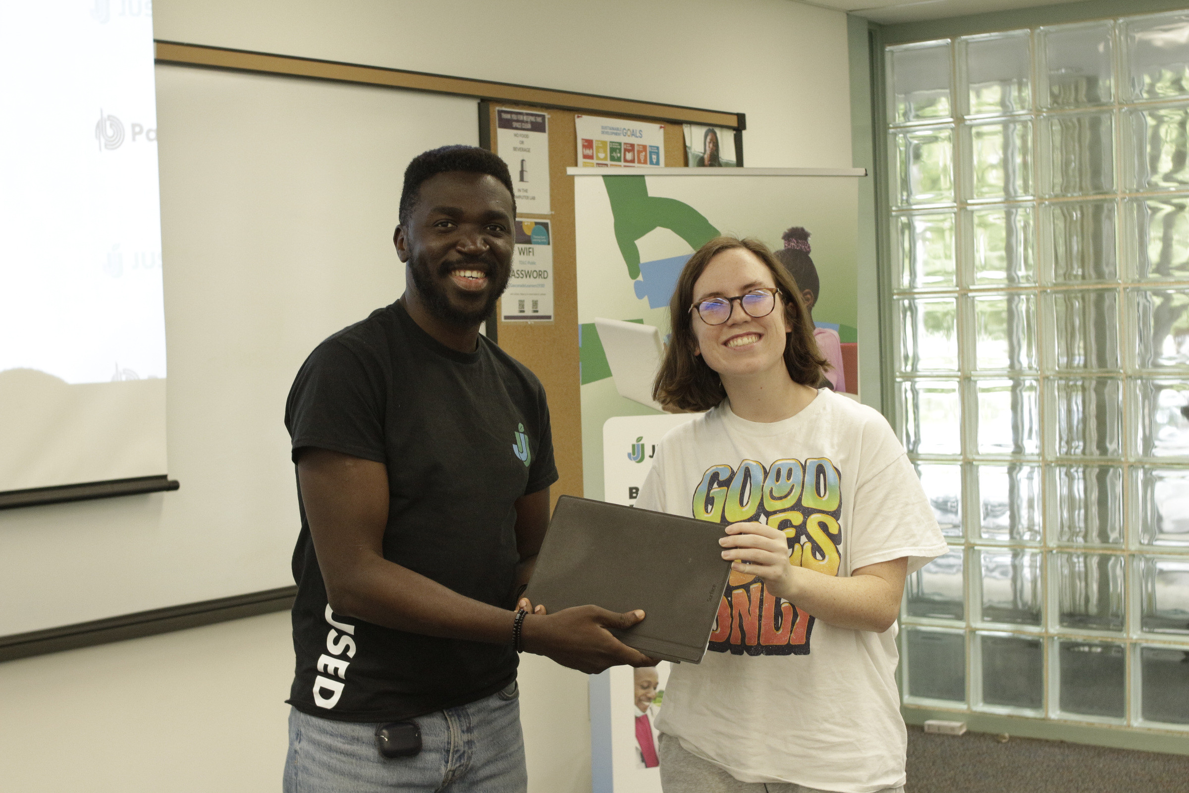A team member and a participant holding a laptop between them for a photograph.