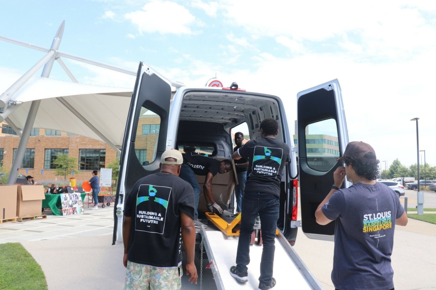 Team members loading equipment into the back of a van at an outdoor collection event.