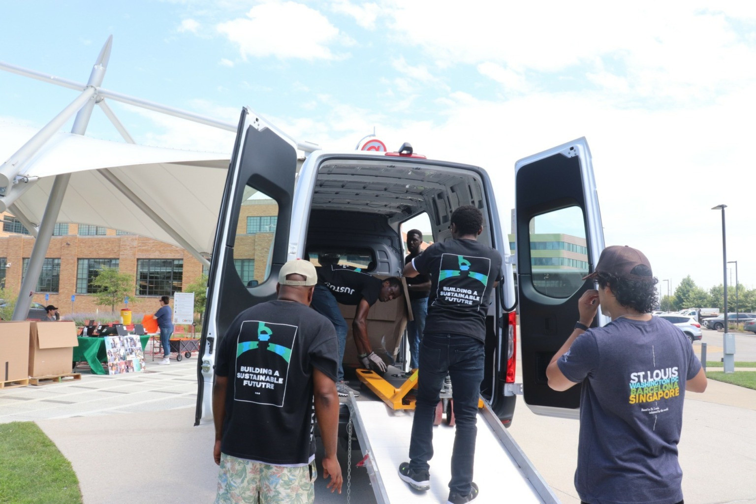 Team members loading equipment into the back of a van at an outdoor collection event.