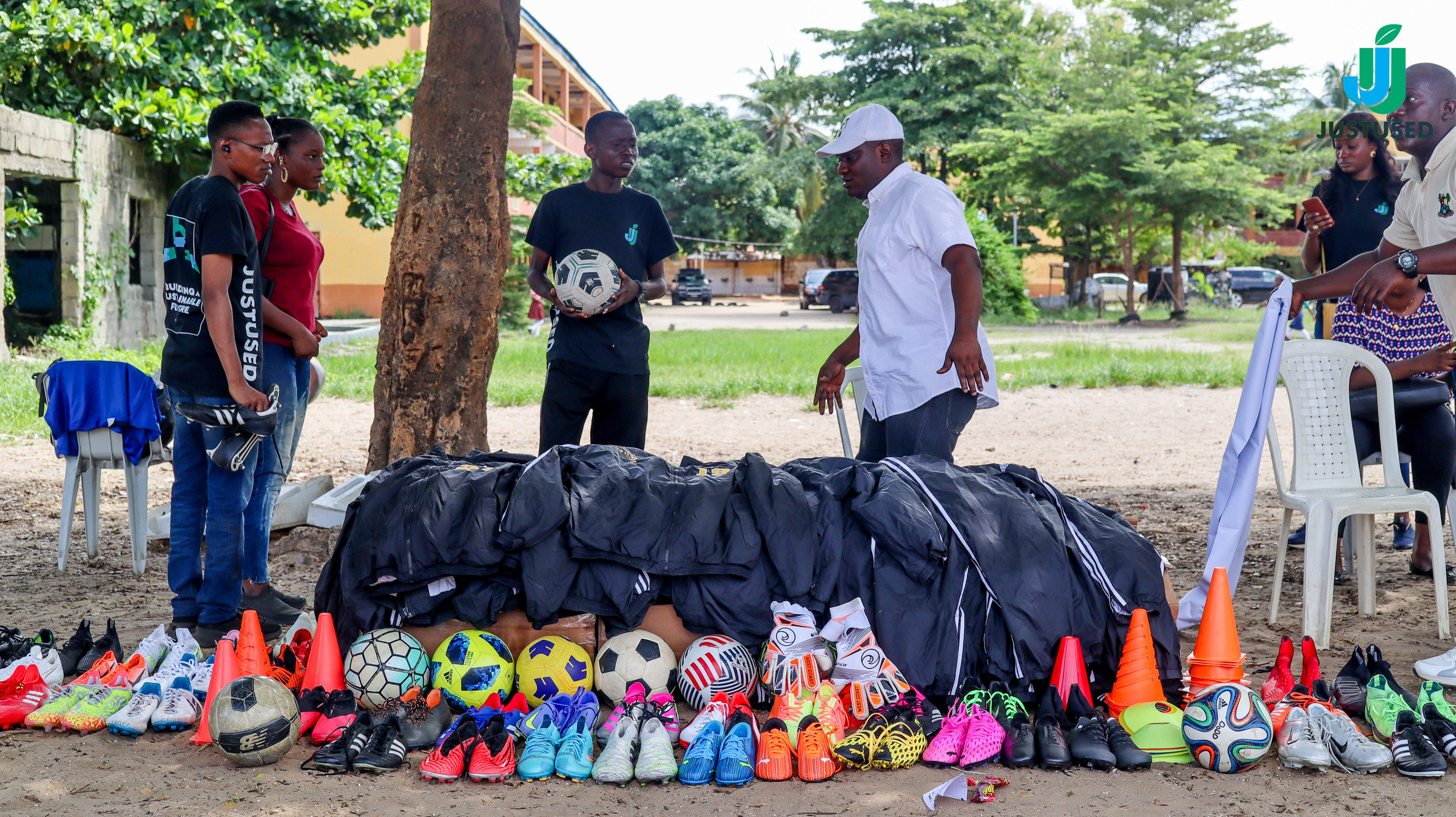 Sports kit bags, boots, balls, and training cones laid out on the ground with people standing behind them.