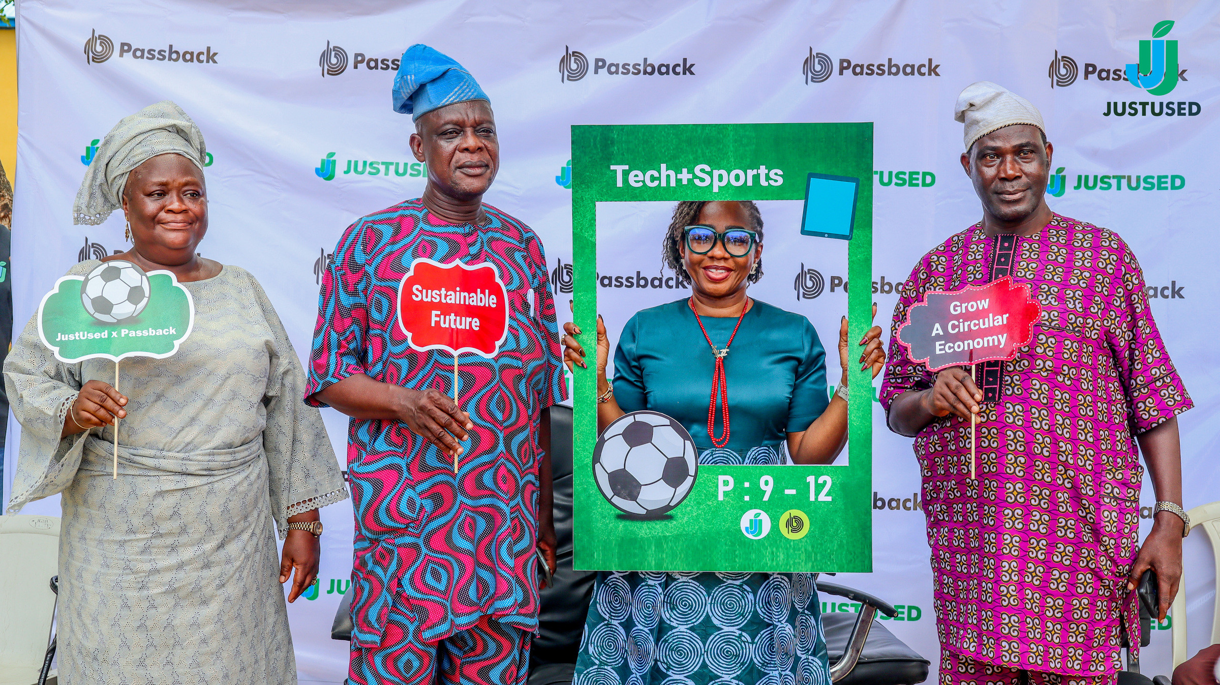 Four people in formal dress standing with Project 9-12 photo props in front of a Passback and JustUsedTech backdrop.